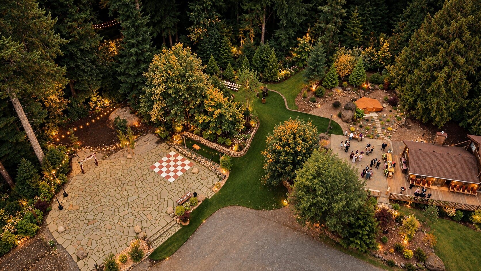 Styled aerial view at dusk: guests on the patio outside the Lodge, the lawn path and the stone patio with its dance floor