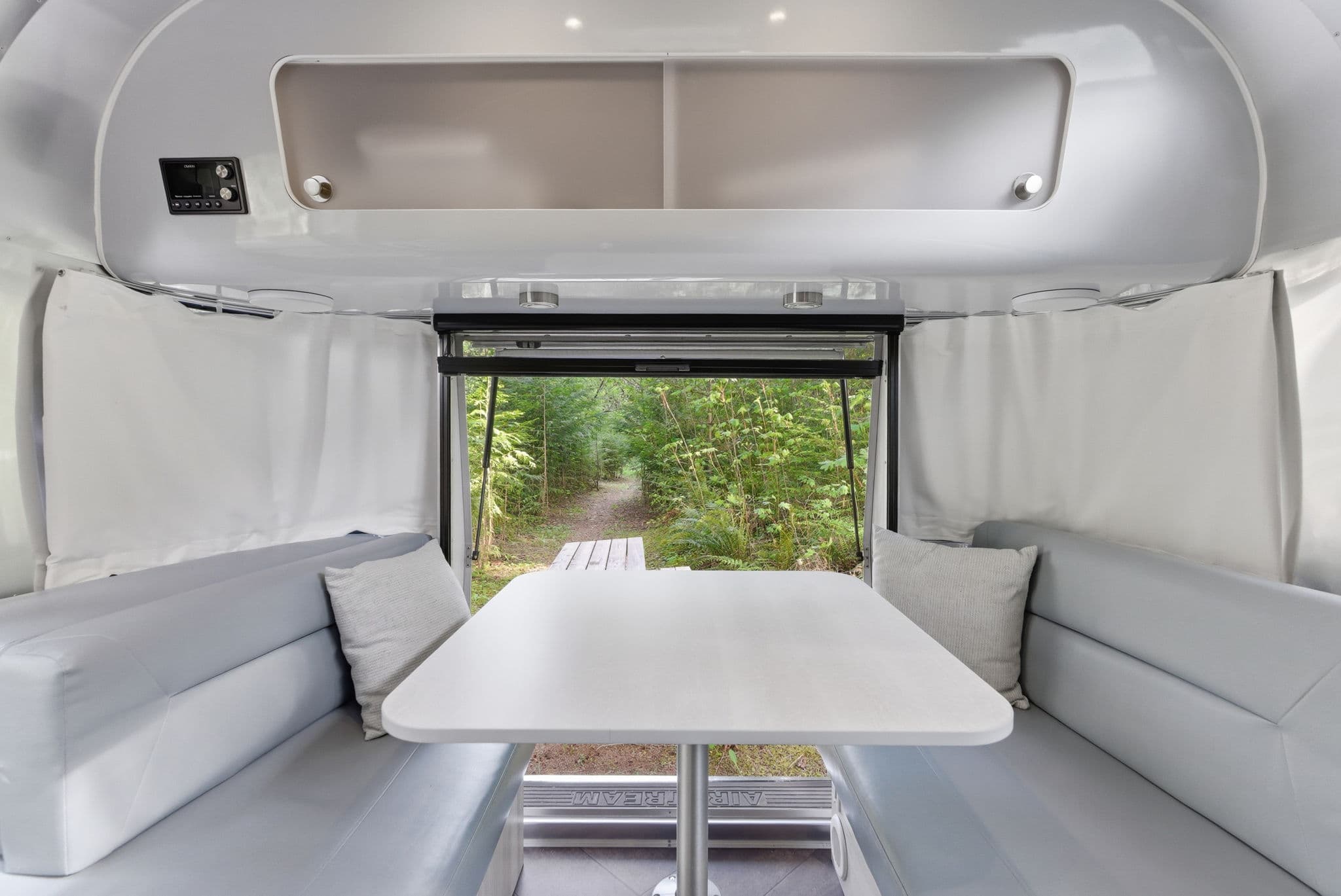 Airstream dining nook with open door to the forest path
