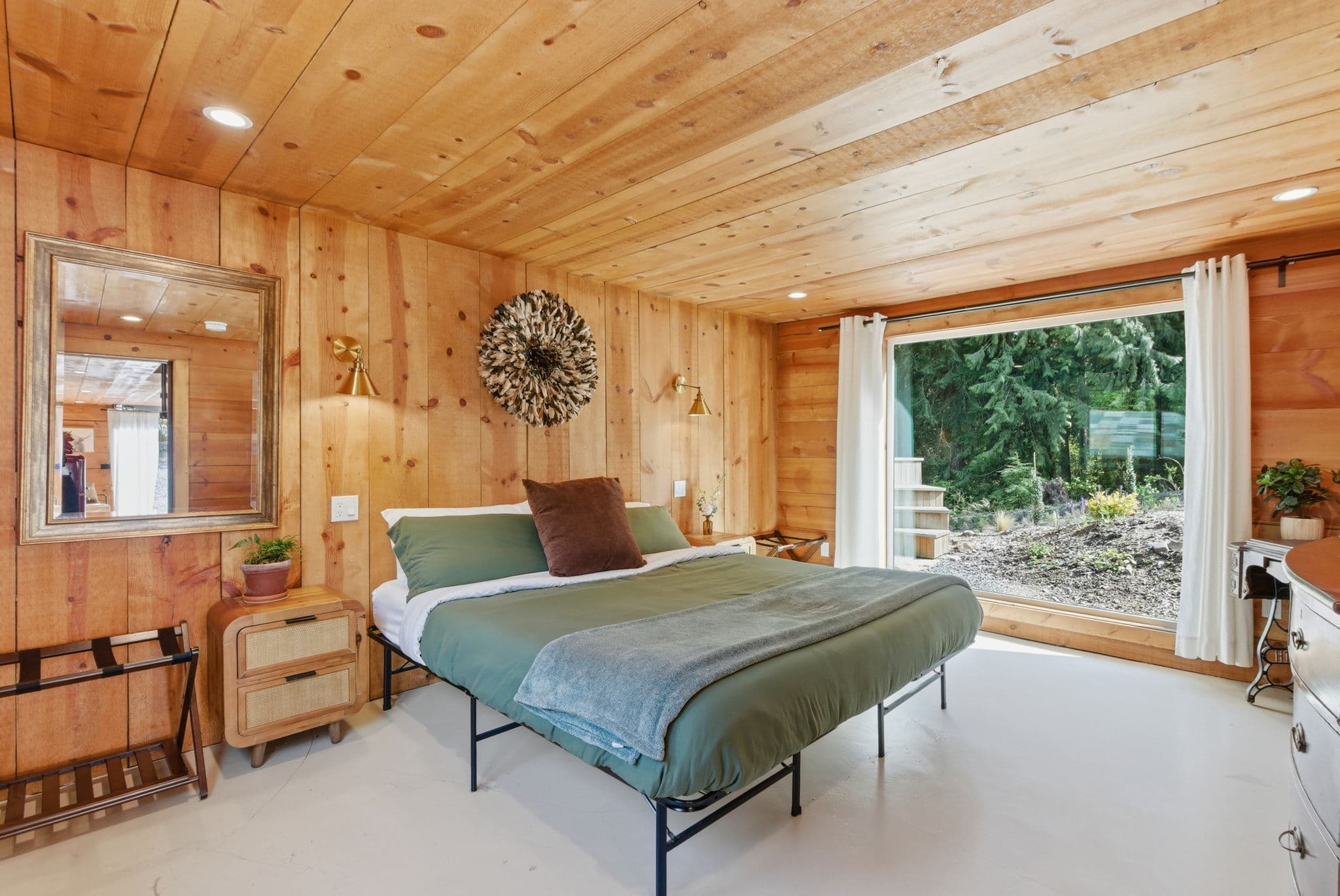 Cottage master bedroom with cedar-plank walls, king bed, and feather wall hanging