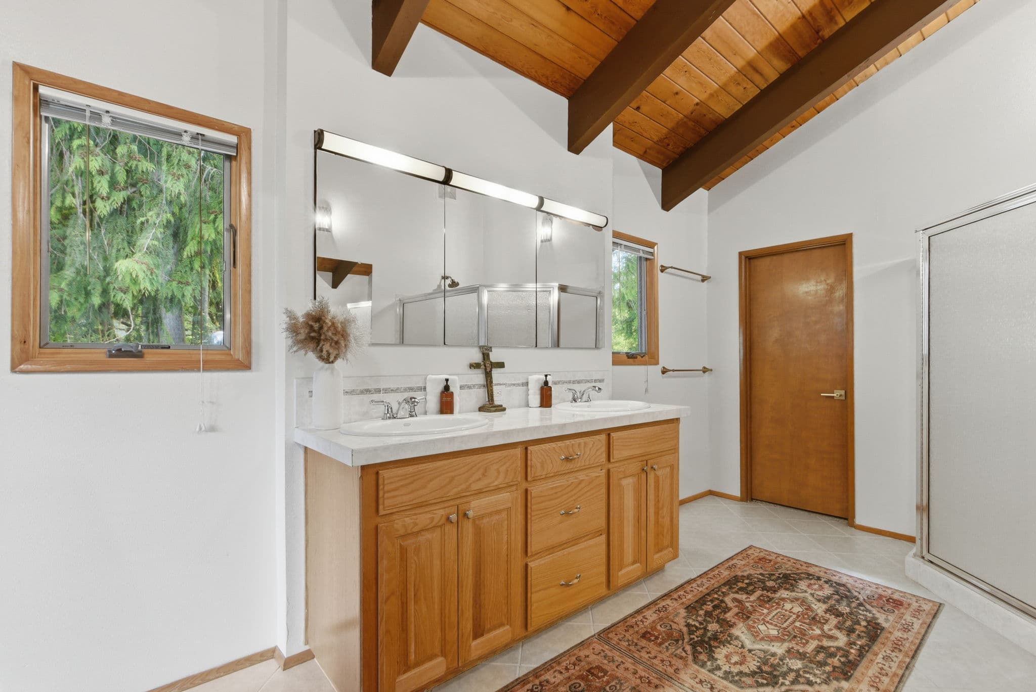Guest bath with vaulted wood-beam ceiling and glass shower stall