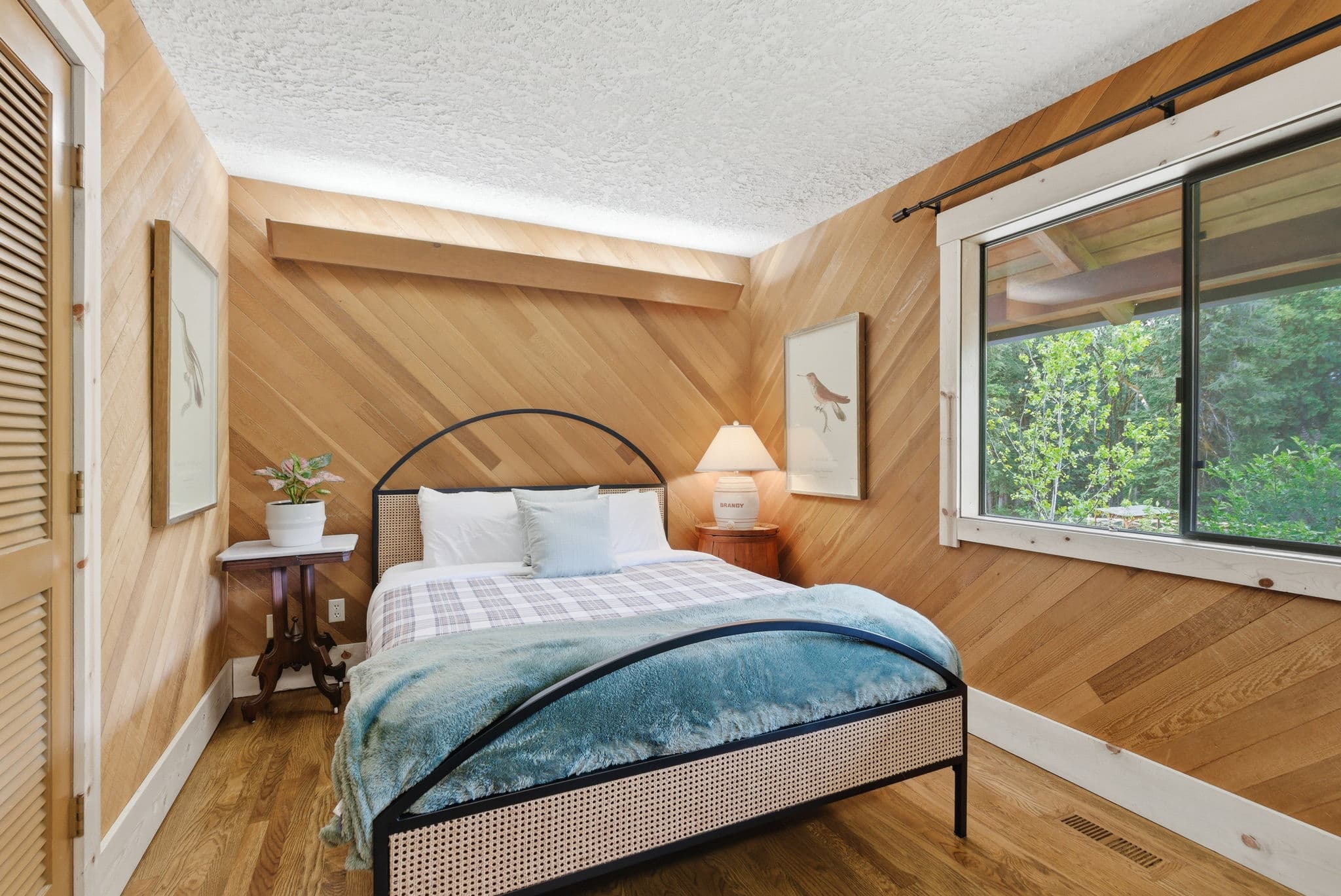 Bedroom with cedar herringbone wood paneling and queen plaid bed