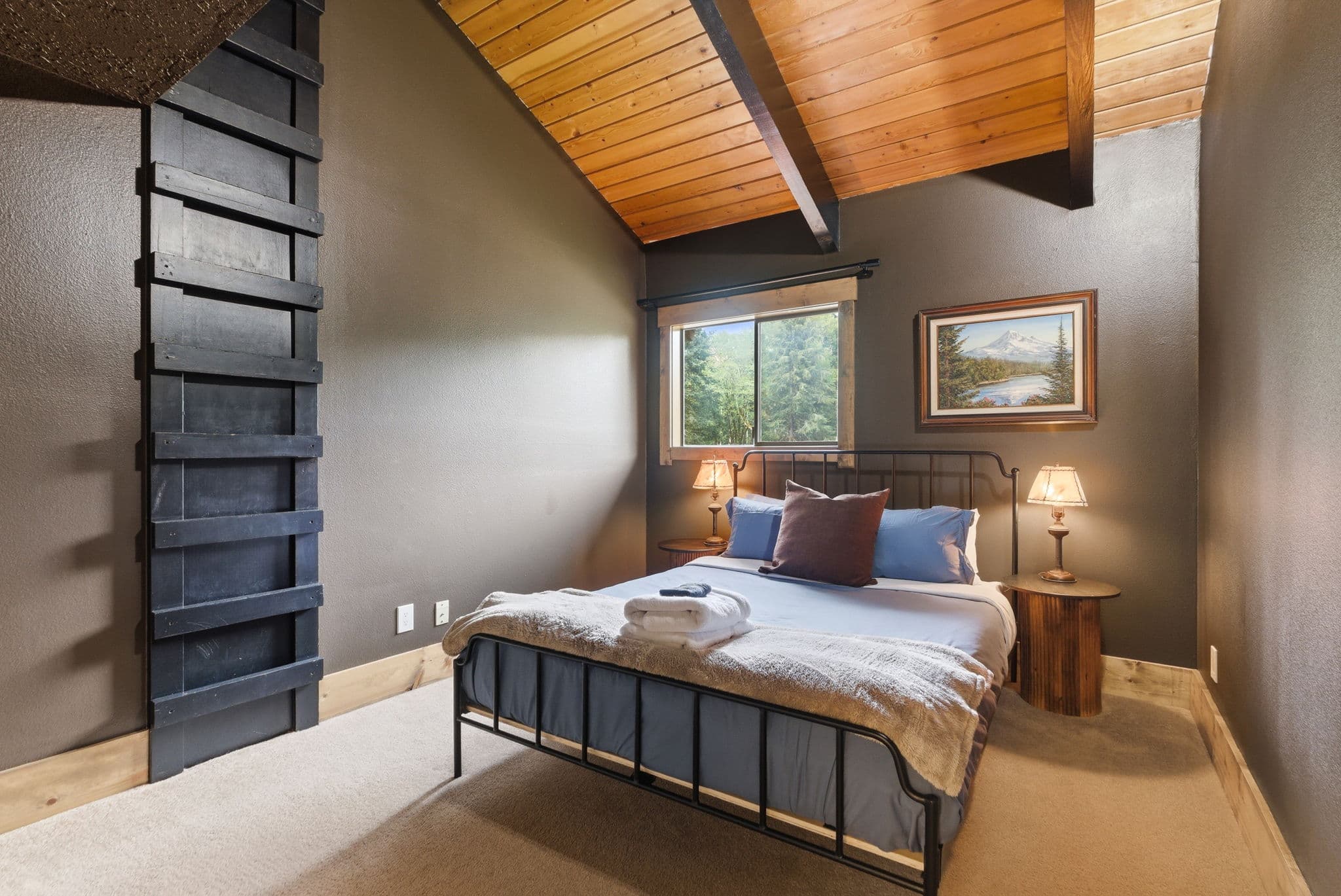 Bedroom with vaulted ceiling, Mt. Hood painting, and ladder up to a hidden loft