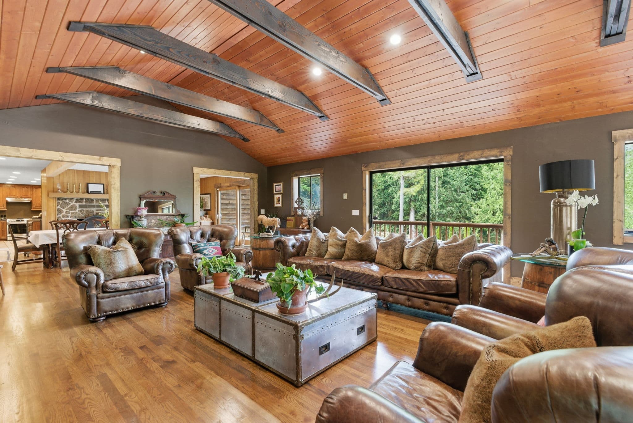 Lodge living room with Chesterfield sofas, stone fireplace, and curved iron-truss ceiling