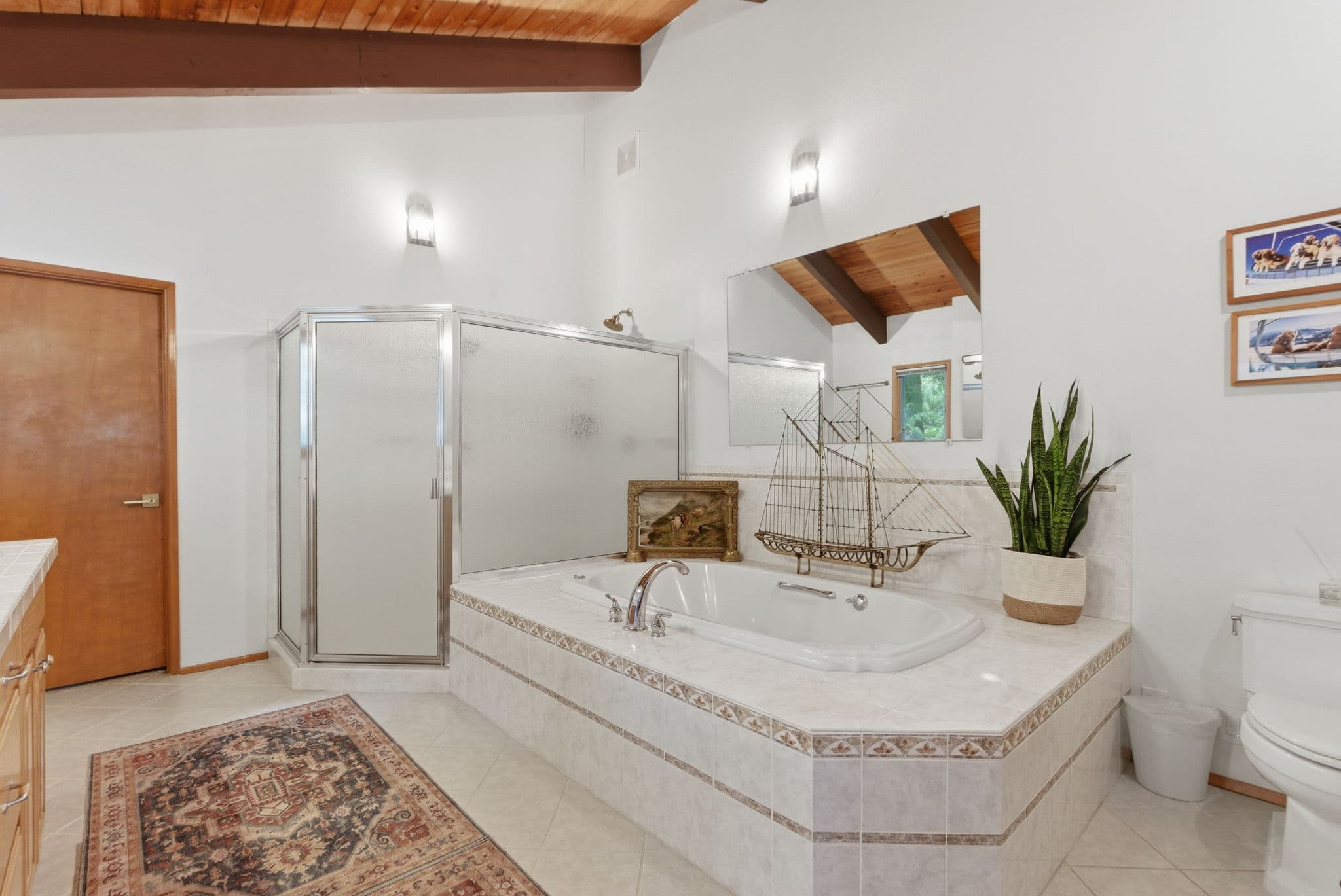 Master bathroom with vaulted wood ceiling, soaking tub, and glass shower