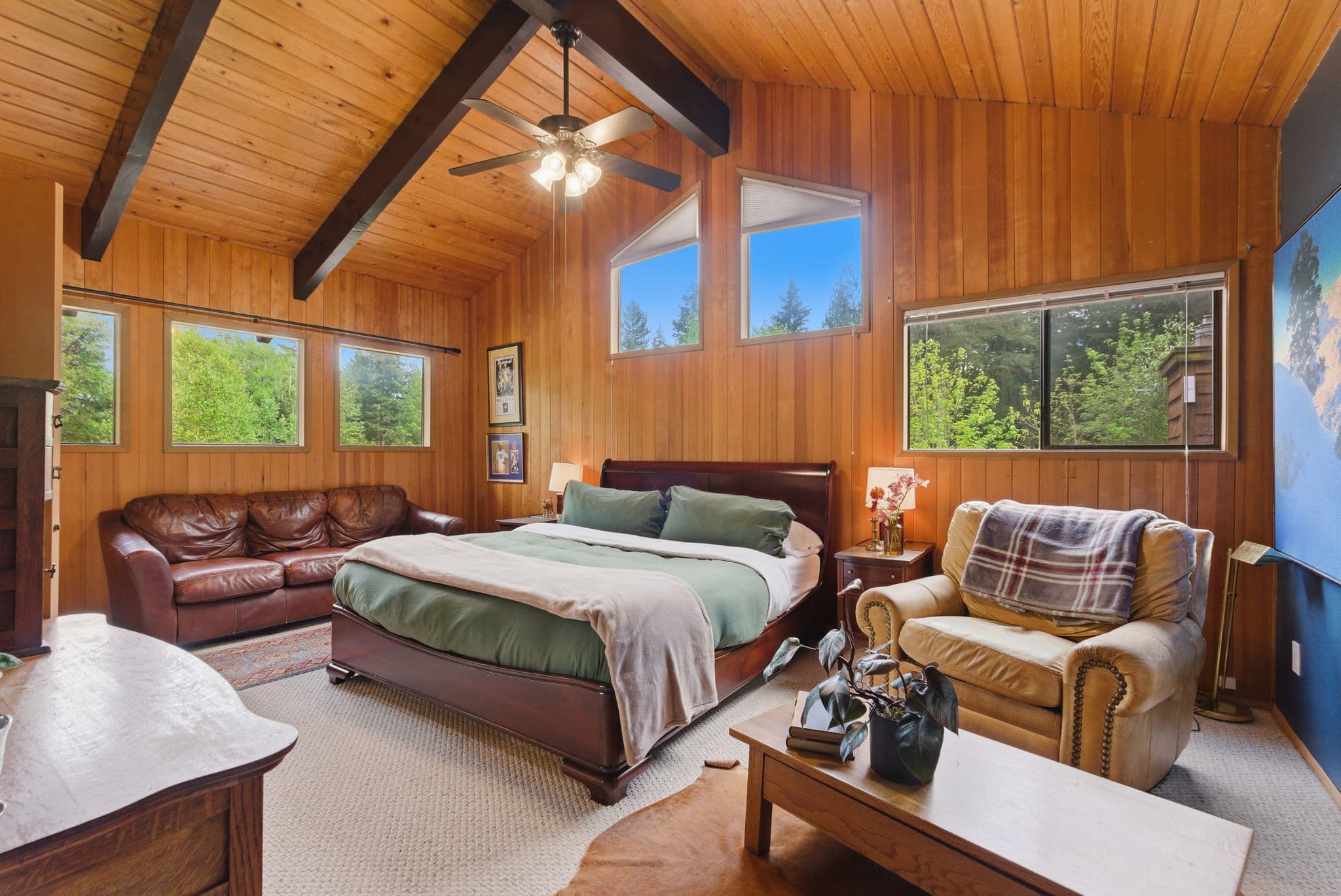Master bedroom with vaulted cedar ceiling, king bed, and forest-view sitting area