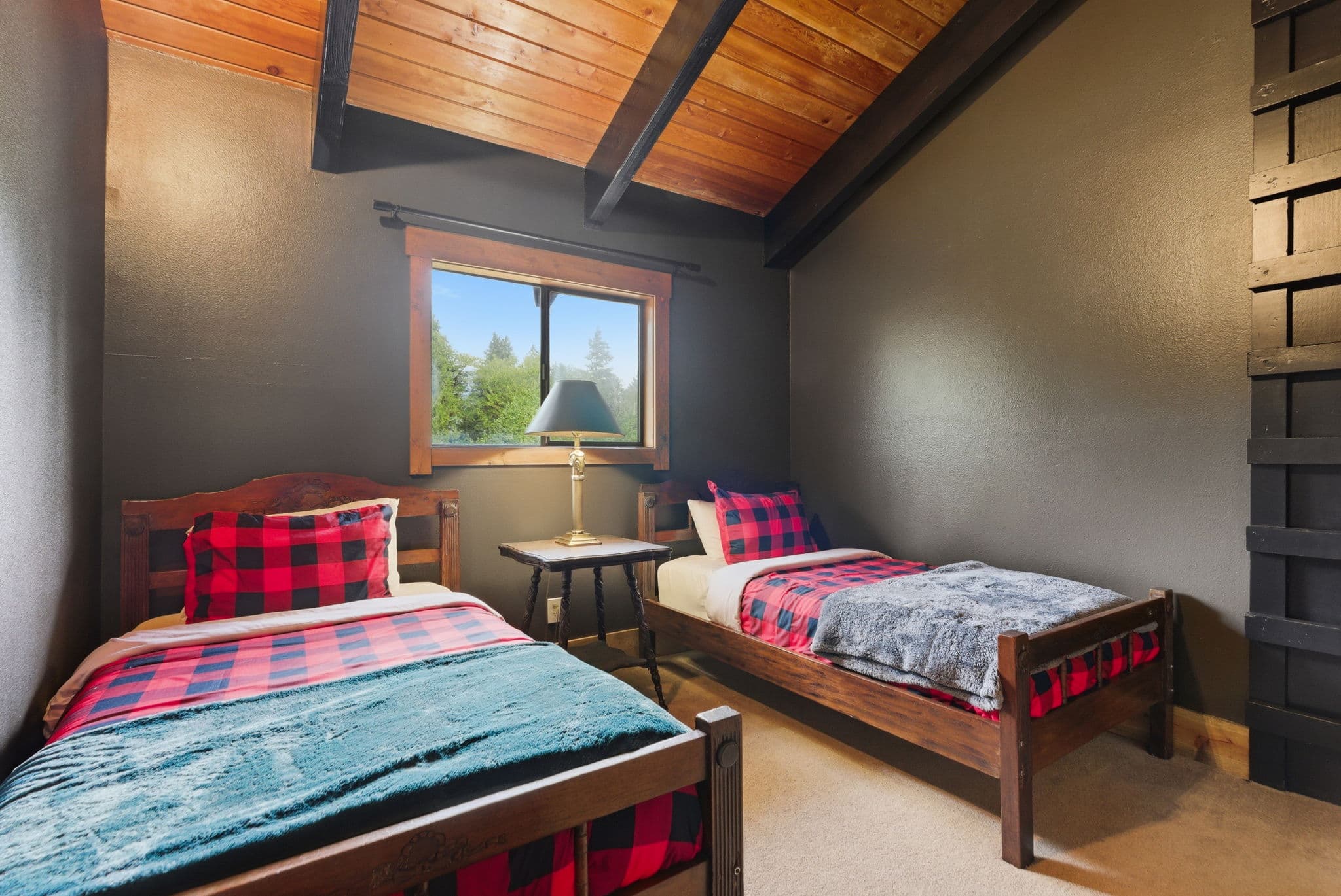 Twin bedroom with lumberjack plaid bedding and vaulted wood ceiling