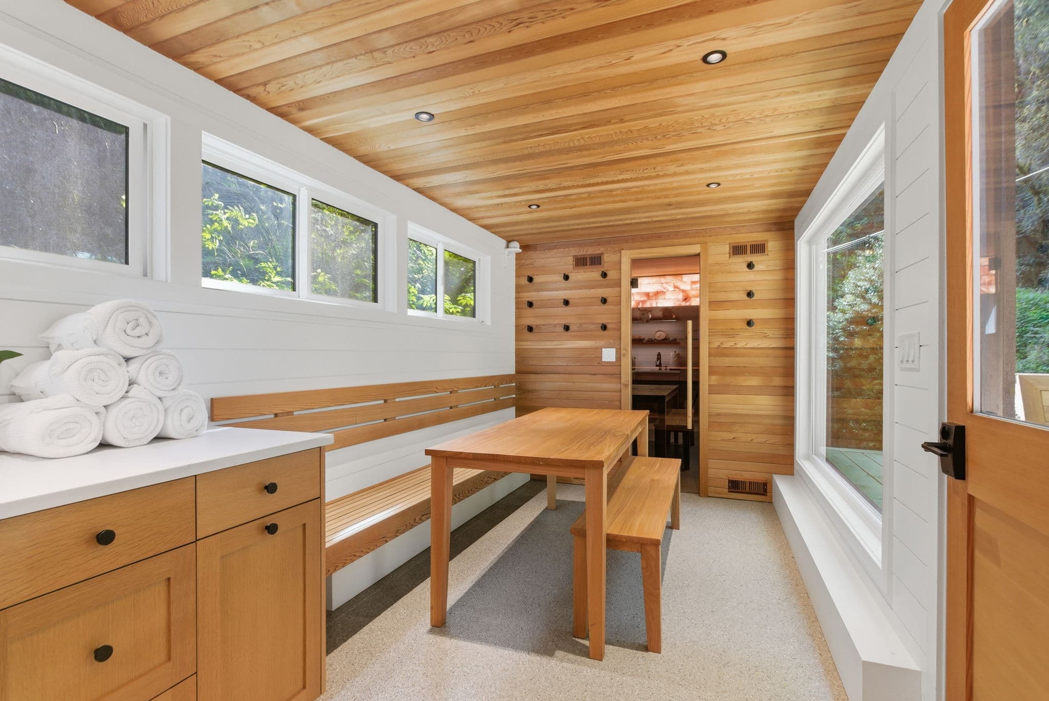 Bench seating with fresh towels and view into the cedar sauna