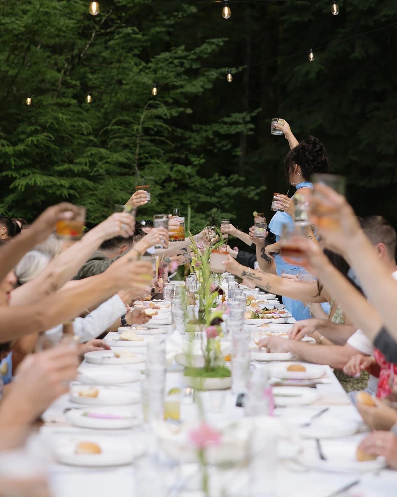 Hands lift glasses in a toast across a candlelit table